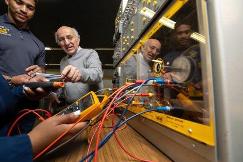 A student is shown how to take instrument readings during a circuits lab.